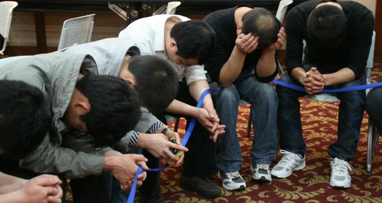 Jovens cristãos chineses em oração silenciosa após participarem de dinâmica de grupo durante fórum de jovens