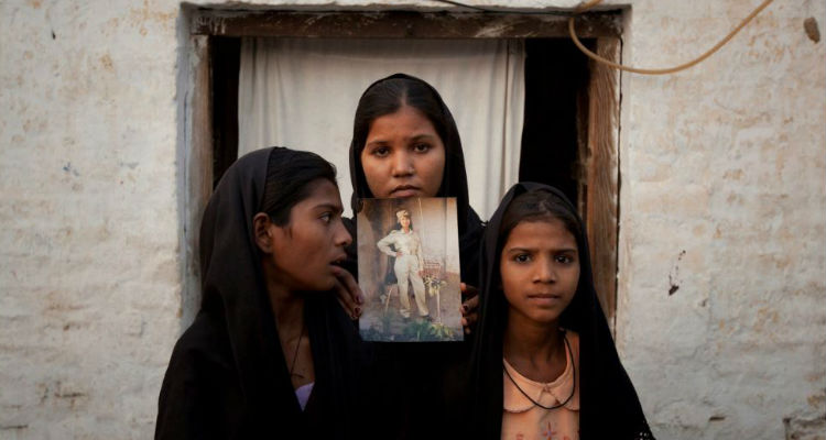 As filhas de Asia Bibi seguram uma imagem da mãe em frente à casa onde moravam em Sheikhupura, no Paquistão (Imagem: The Sunday Telegraph)